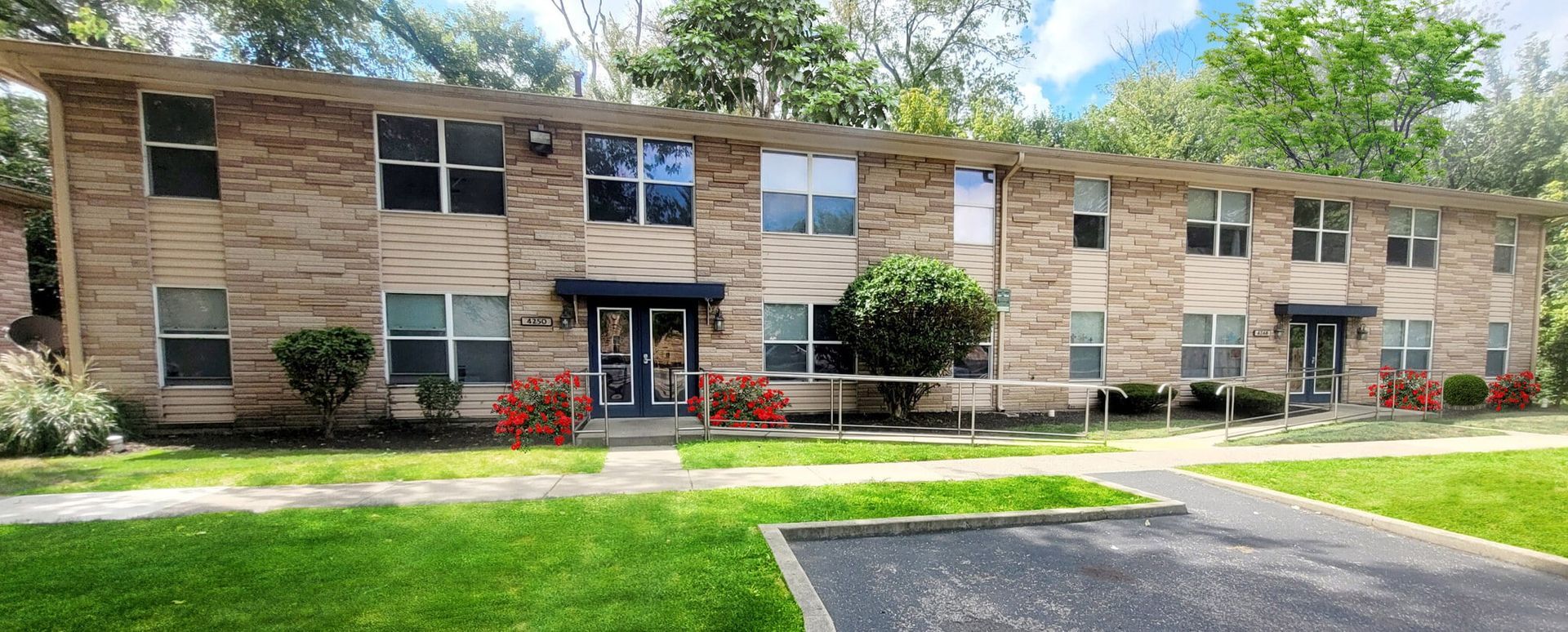 A large brick apartment building with a lot of windows and a parking lot in front of it.