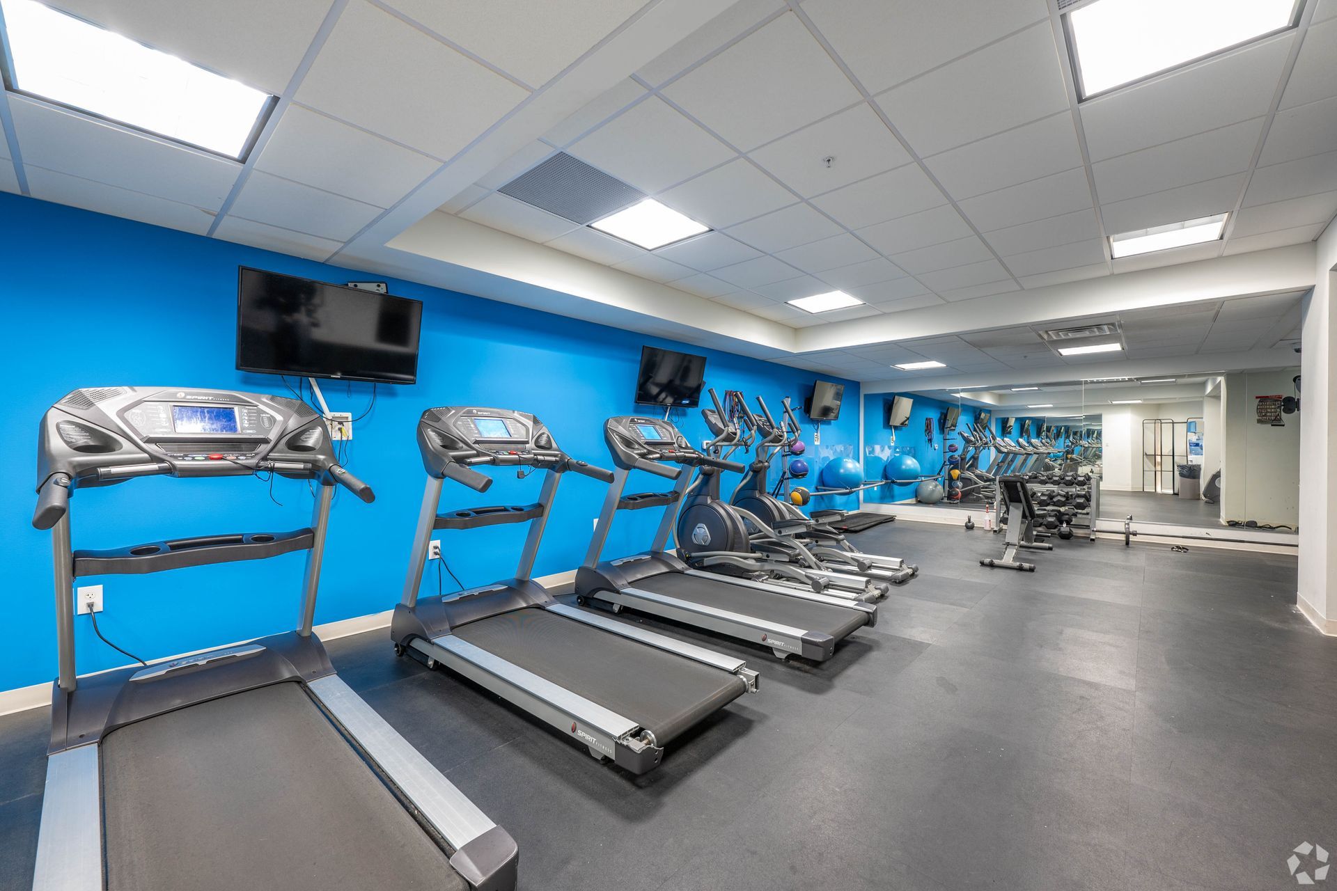 A gym with a lot of treadmills and a large mirror.