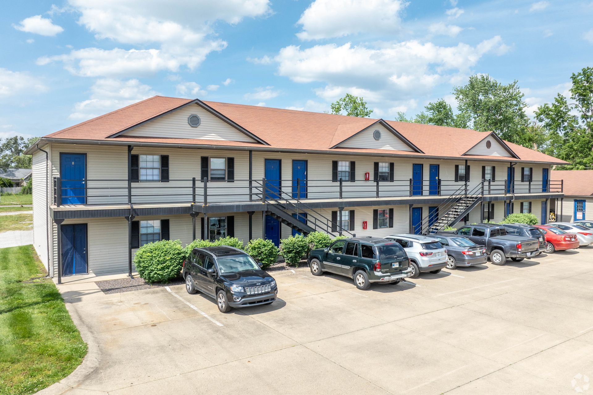 A large apartment building with a lot of cars parked in front of it.