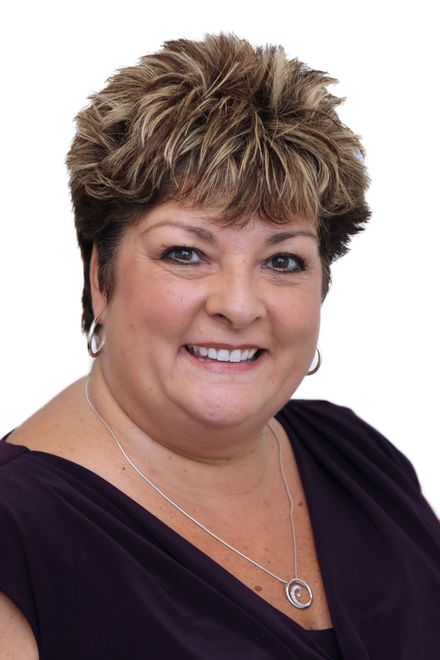 Portrait of a smiling woman in a dark purple top on a white background