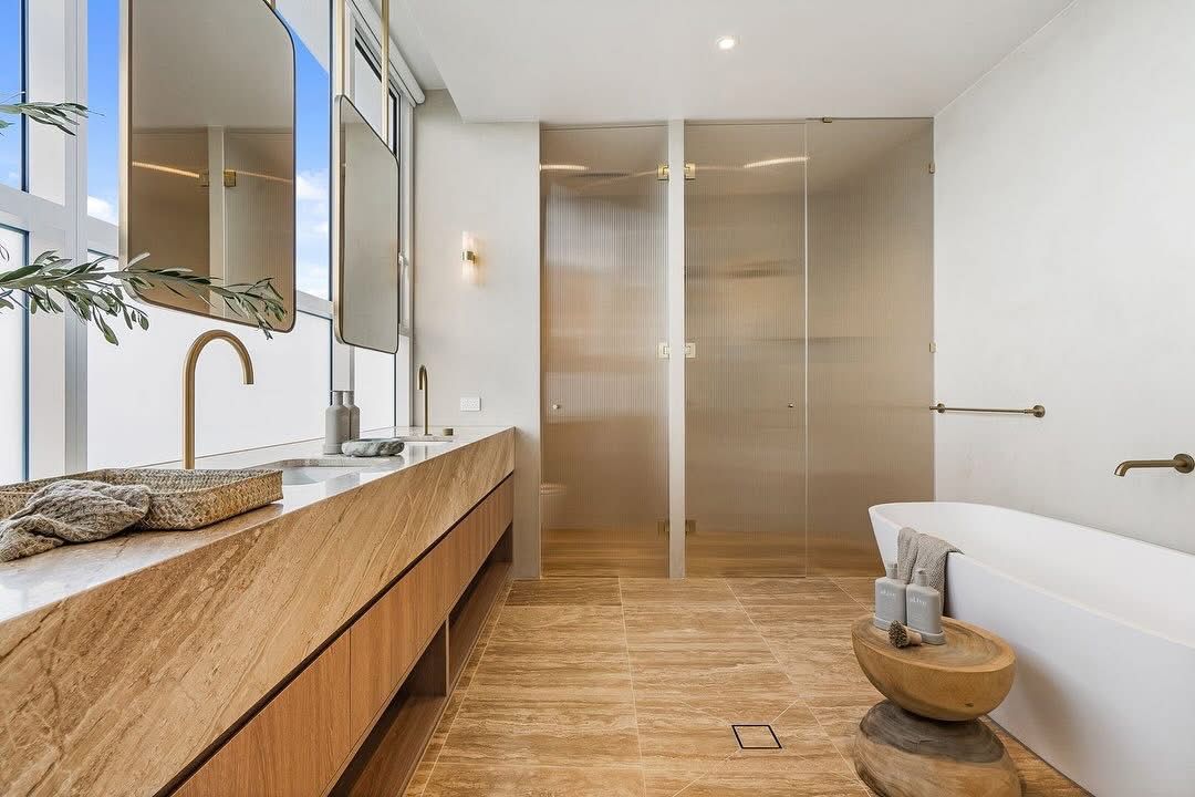 A light colour stone bathroom counter top with two mirrors and gold accessories — Universal Marble & Granite In Woolgoolga, NSW