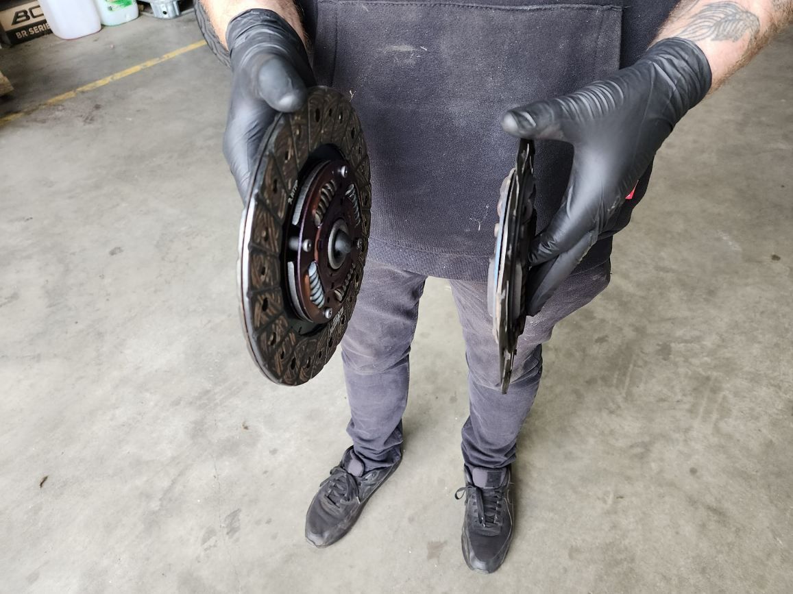 A Man Holding Two Clutch Discs — JJ's Garage In South Geelong, VIC