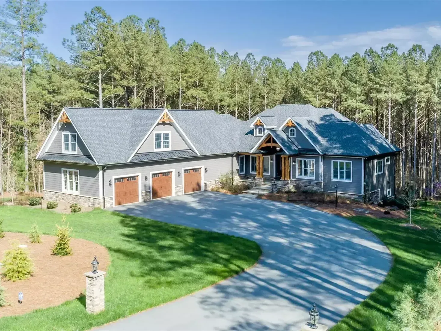 A large house with a driveway leading to it is surrounded by trees