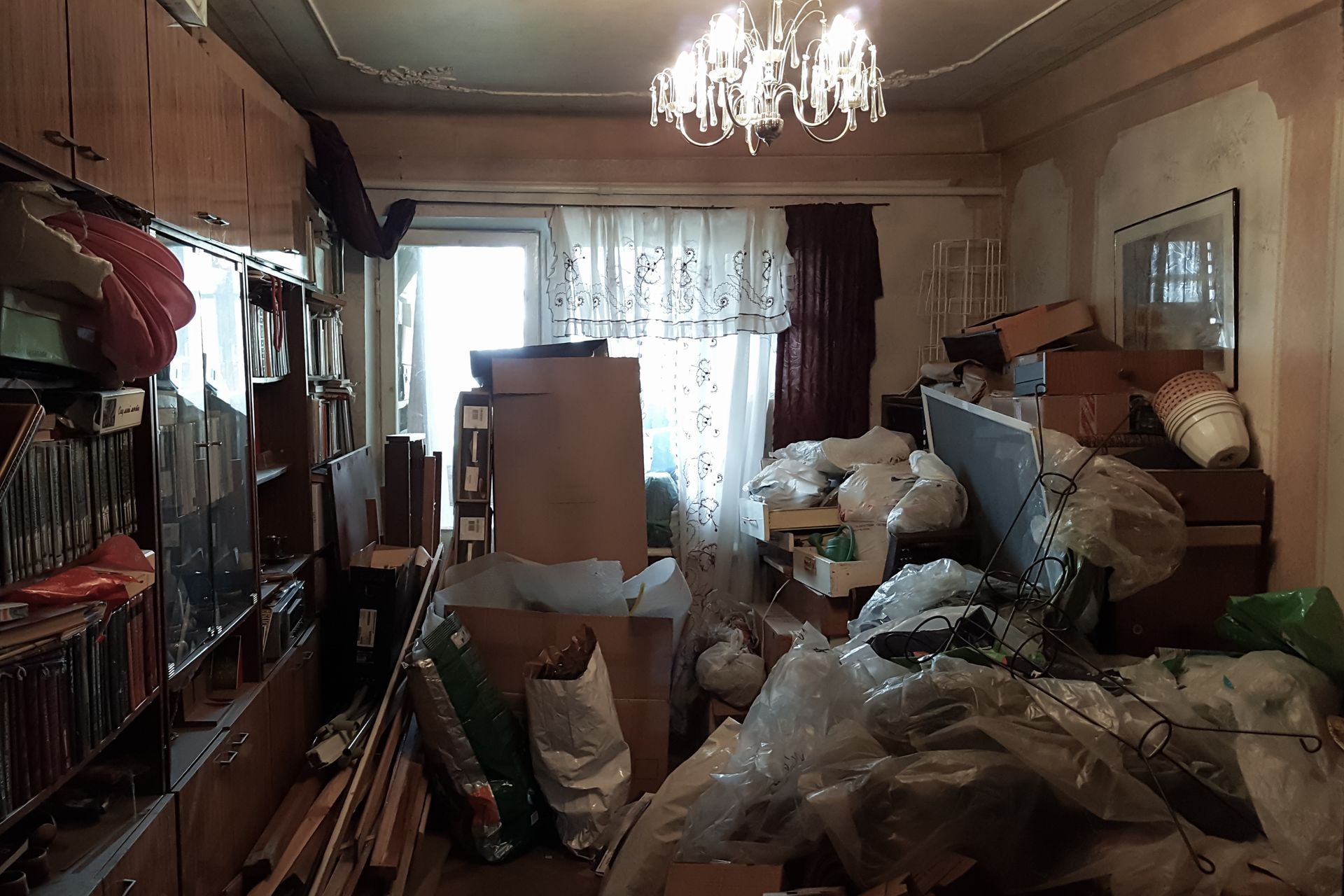 A living room filled with lots of boxes and a chandelier.