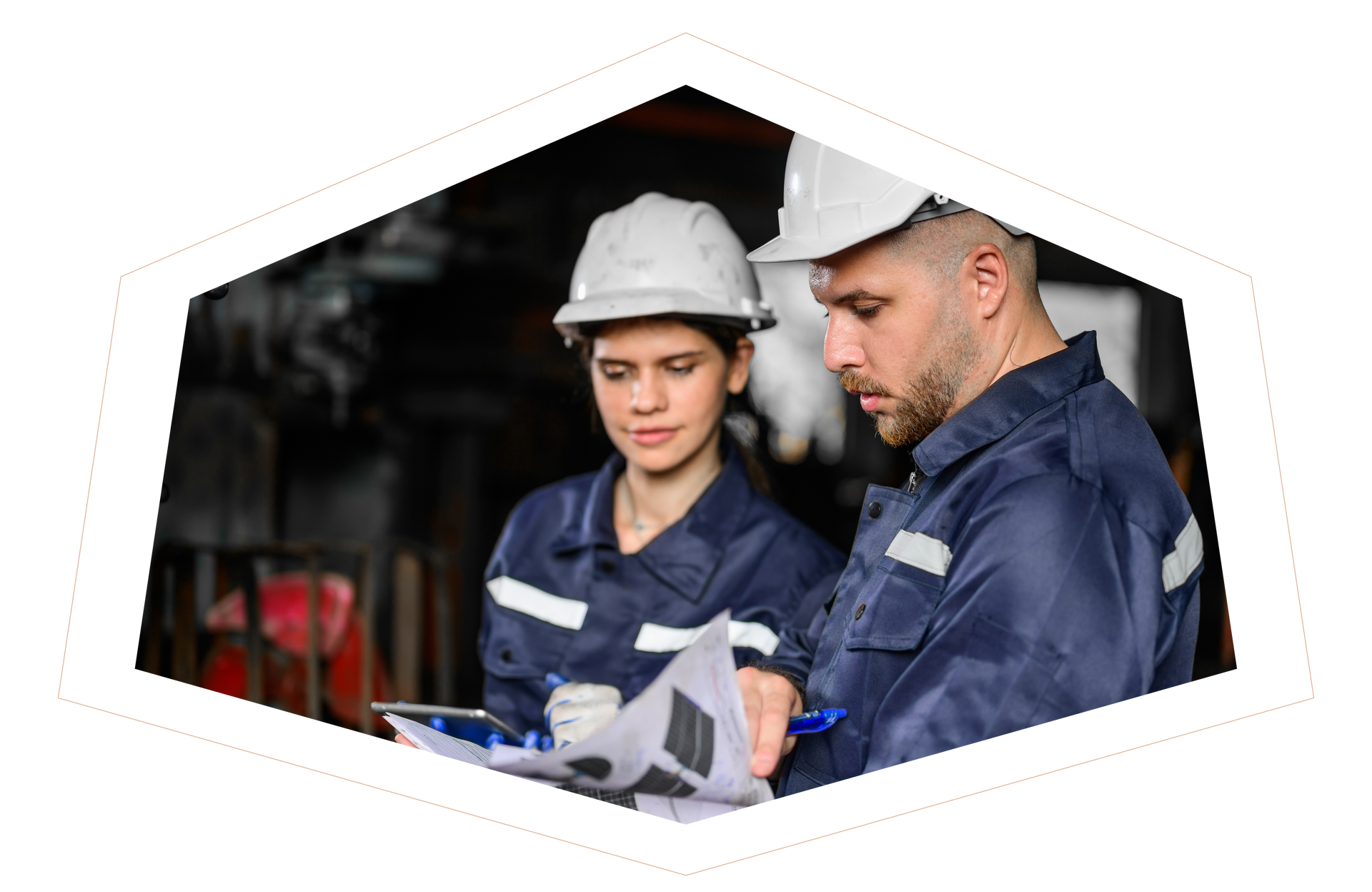 A man and a woman in hard hats are looking at a clipboard.