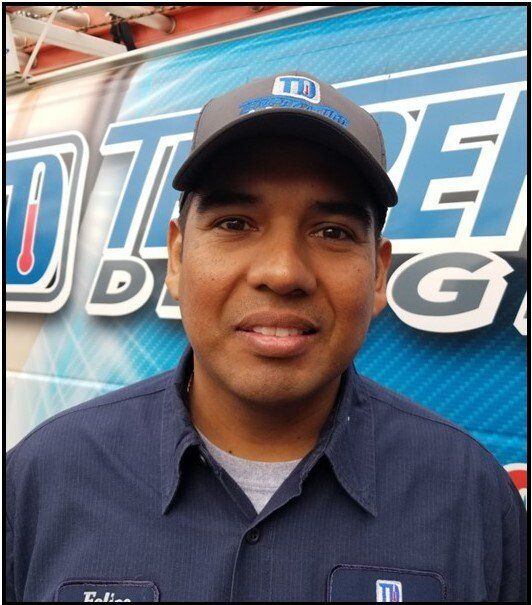 Man in blue shirt and cap standing in front of a blue branded backdrop