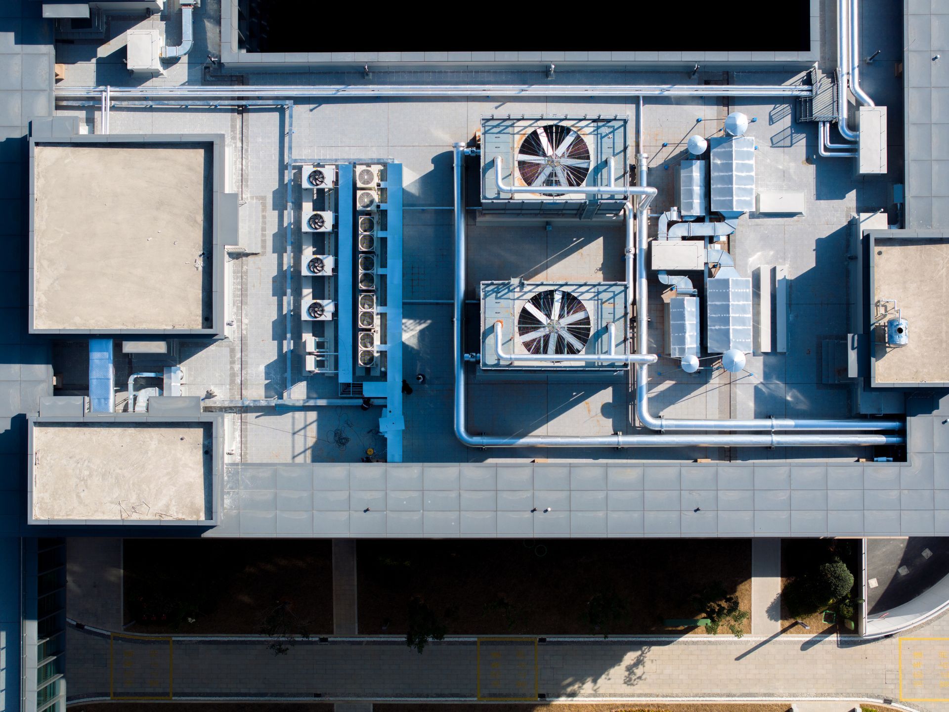 Aerial view of a rooftop with HVAC units, vents, and ductwork in a gray industrial building.