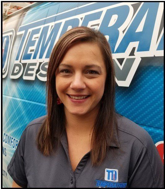 Woman smiling in front of a blue “Tierra” event banner, wearing a gray collared shirt.