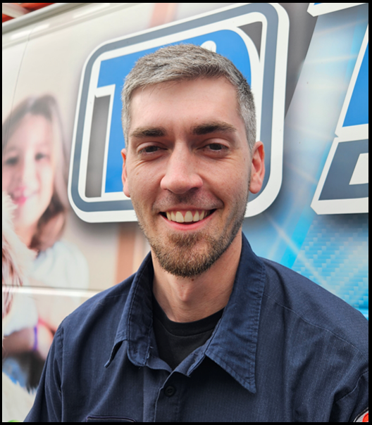 Smiling man in a navy shirt standing before a blue event banner