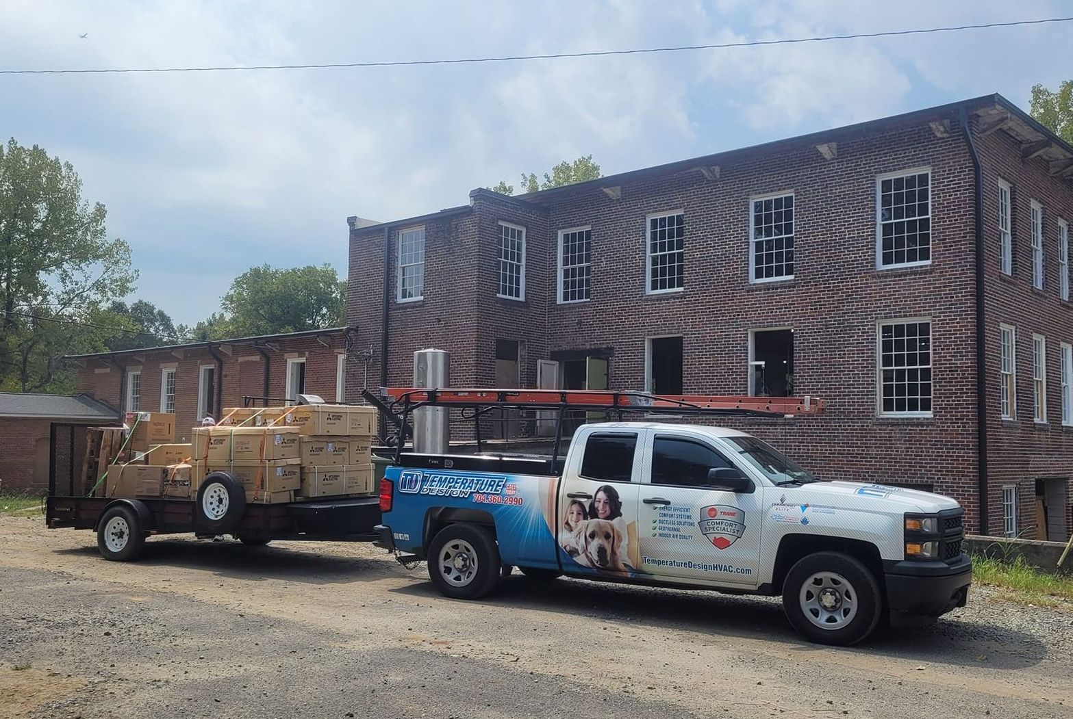Pickup truck towing a cargo trailer in front of a brick building with boarded windows.