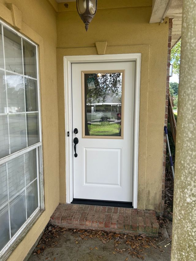 Front porch with a white door, window, and concrete step under a covered entryway.