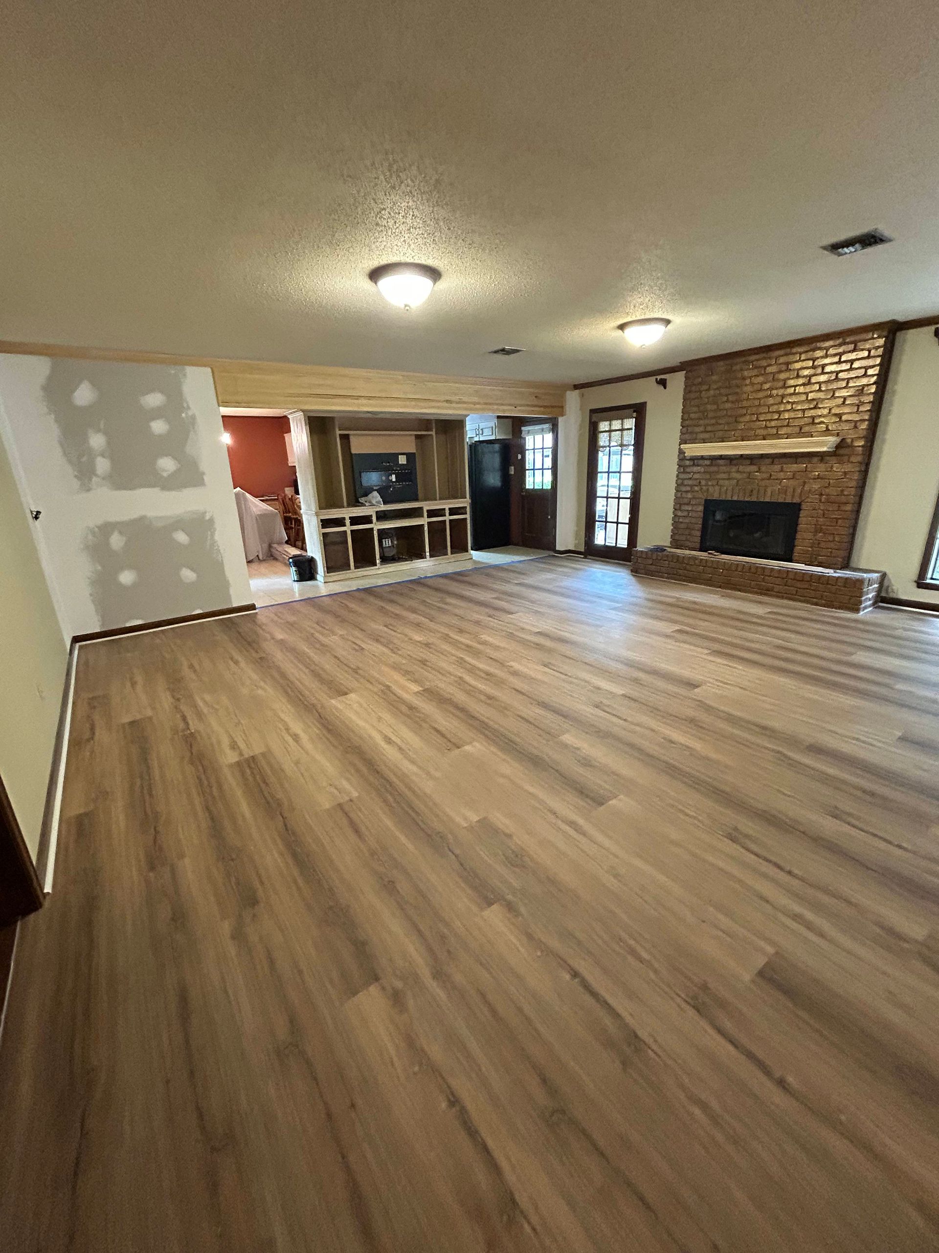 Empty living room with wood flooring, fireplace, and unfinished drywall near the entry.