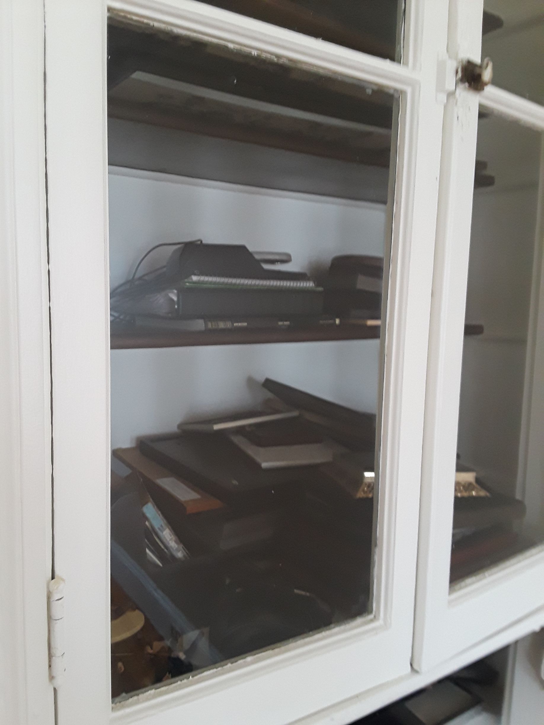 White cabinet with glass doors containing items on shelves.