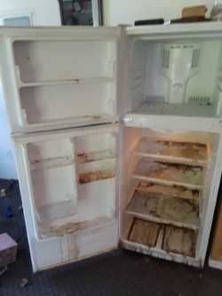 An empty refrigerator with the door open in a room.