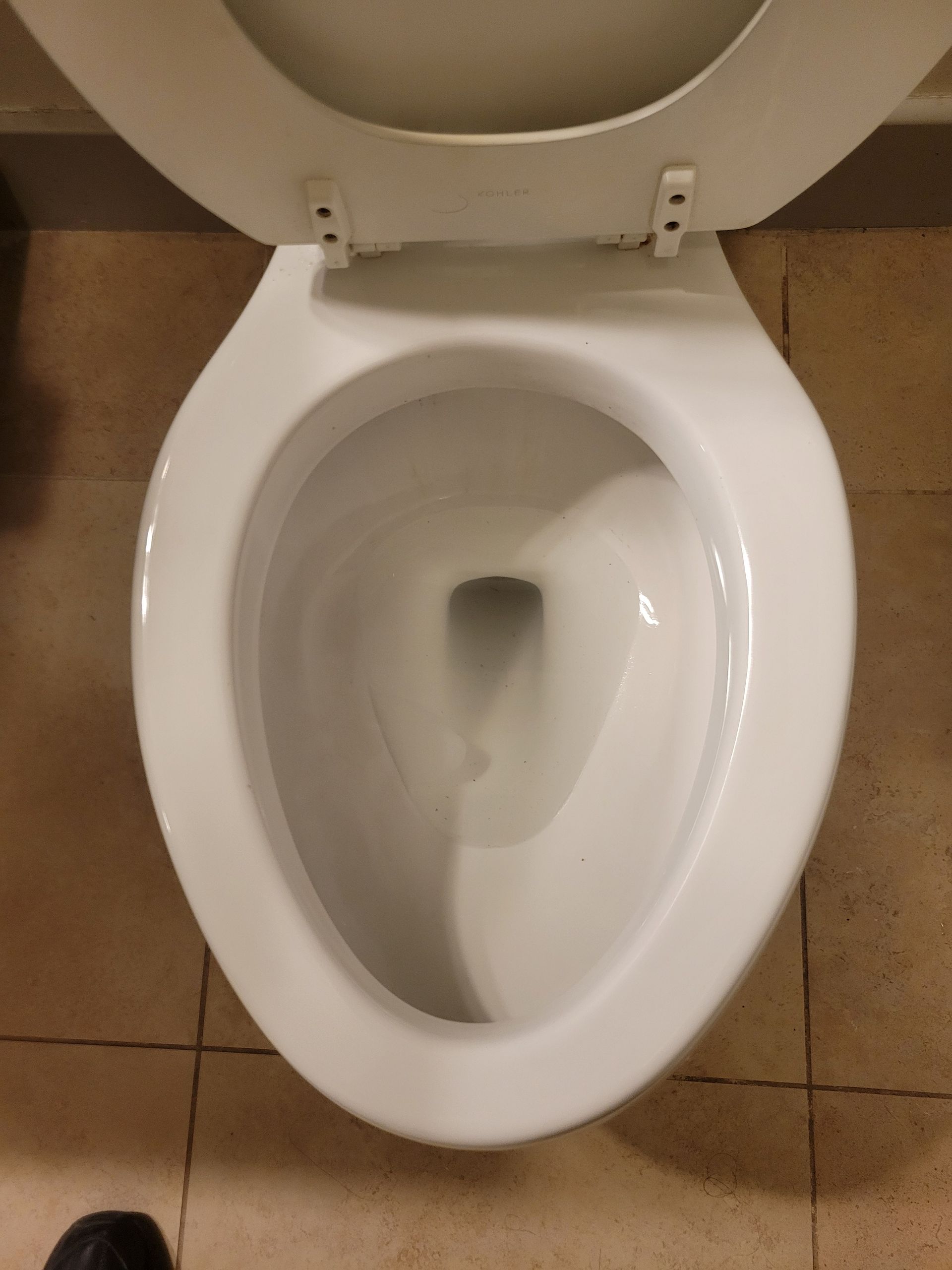 A white toilet sits on a tiled floor with the lid up