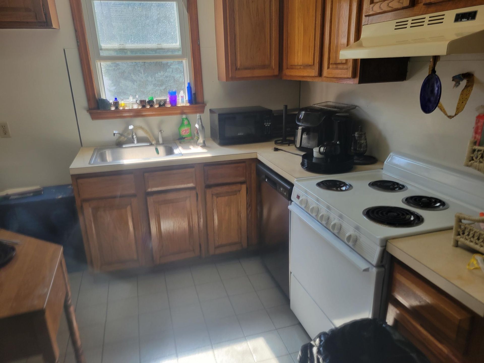 Small kitchen with wooden cabinets, appliances, and a window.