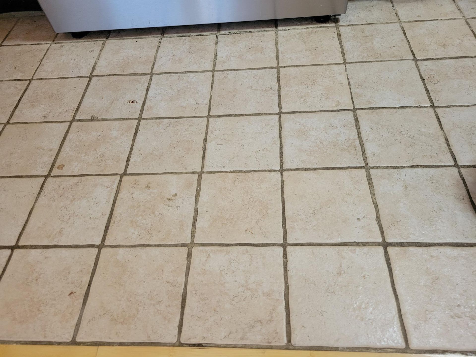 Tan tiled floor with dark grout.