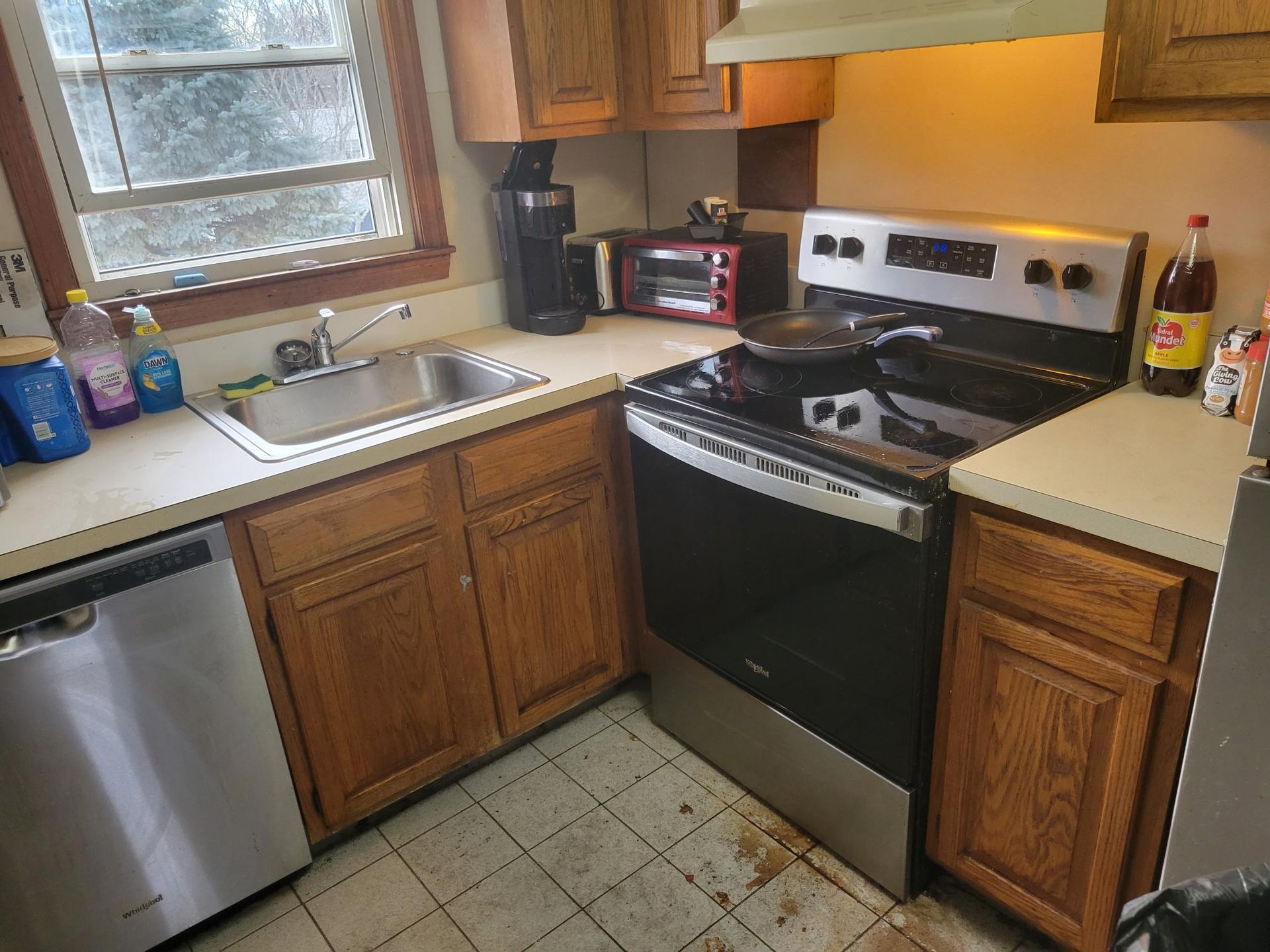 Kitchen with stainless steel appliances, oak cabinets, and a sink by a window.
