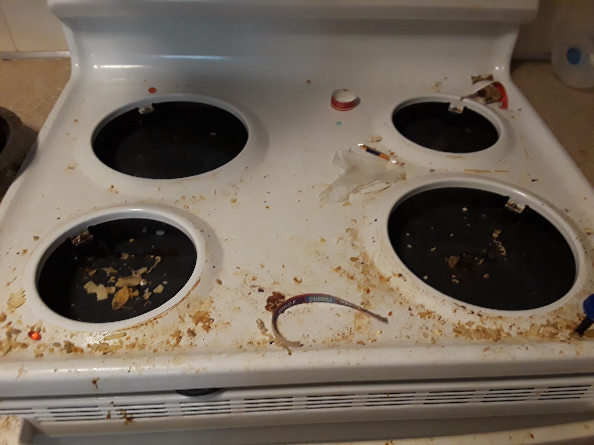 Dirty white electric stovetop with food debris around the burners.