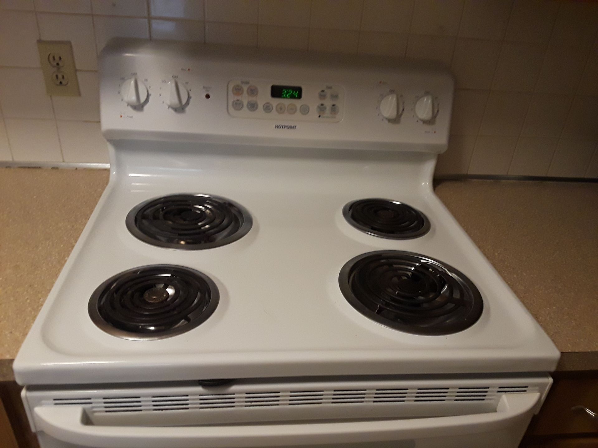 White electric stove with four burners, controls, and oven.