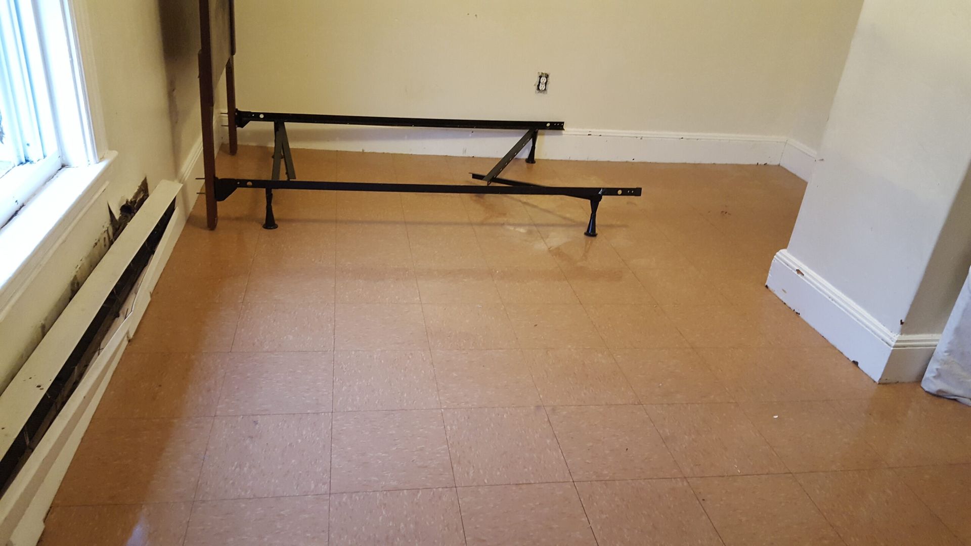 An empty room with a bed frame on the floor.