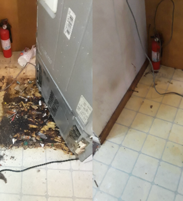 A fire extinguisher is next to a broken refrigerator