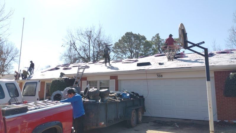 Roofers working on a white roof of a house under a bright, clear sky. 