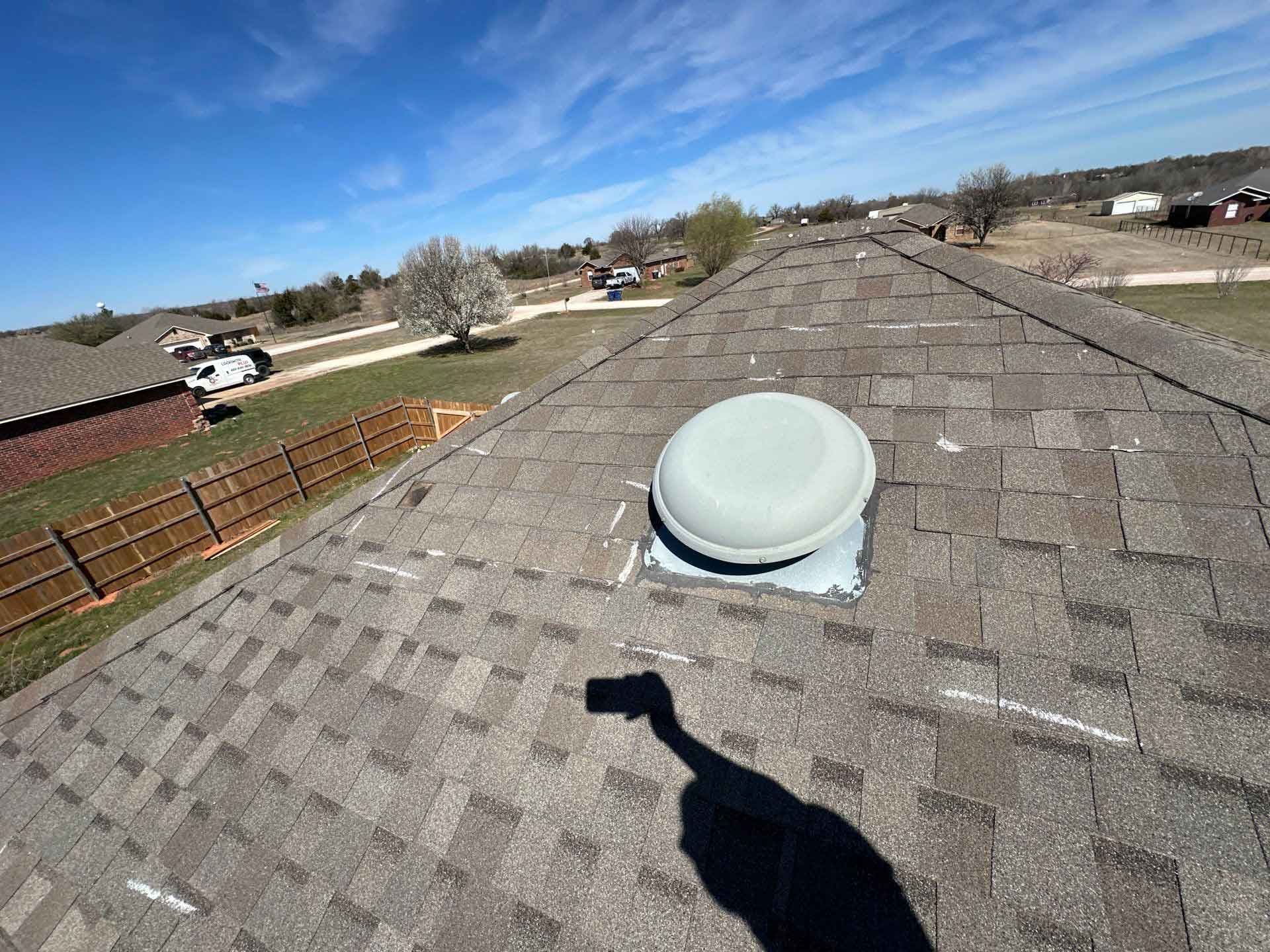A roof with a fan on it and a shadow of a person on it.