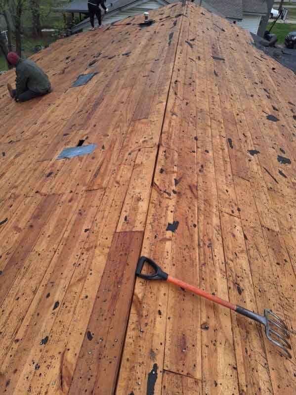 A man is working on a wooden roof with a shovel.