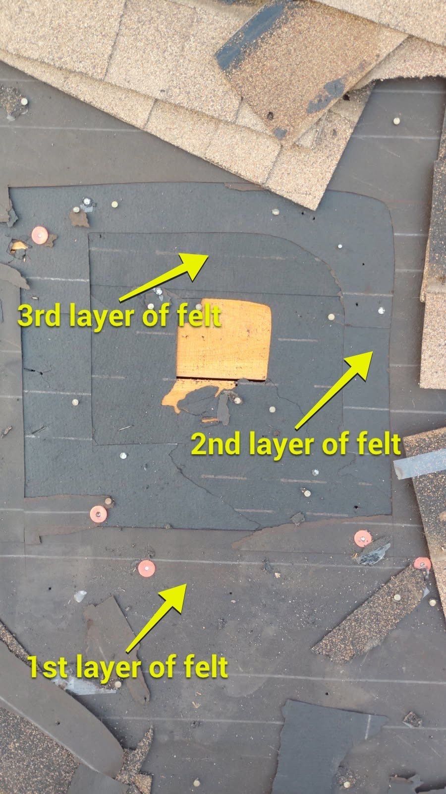 Overhead view of roof layers revealing three layers of felt surrounding a square opening.