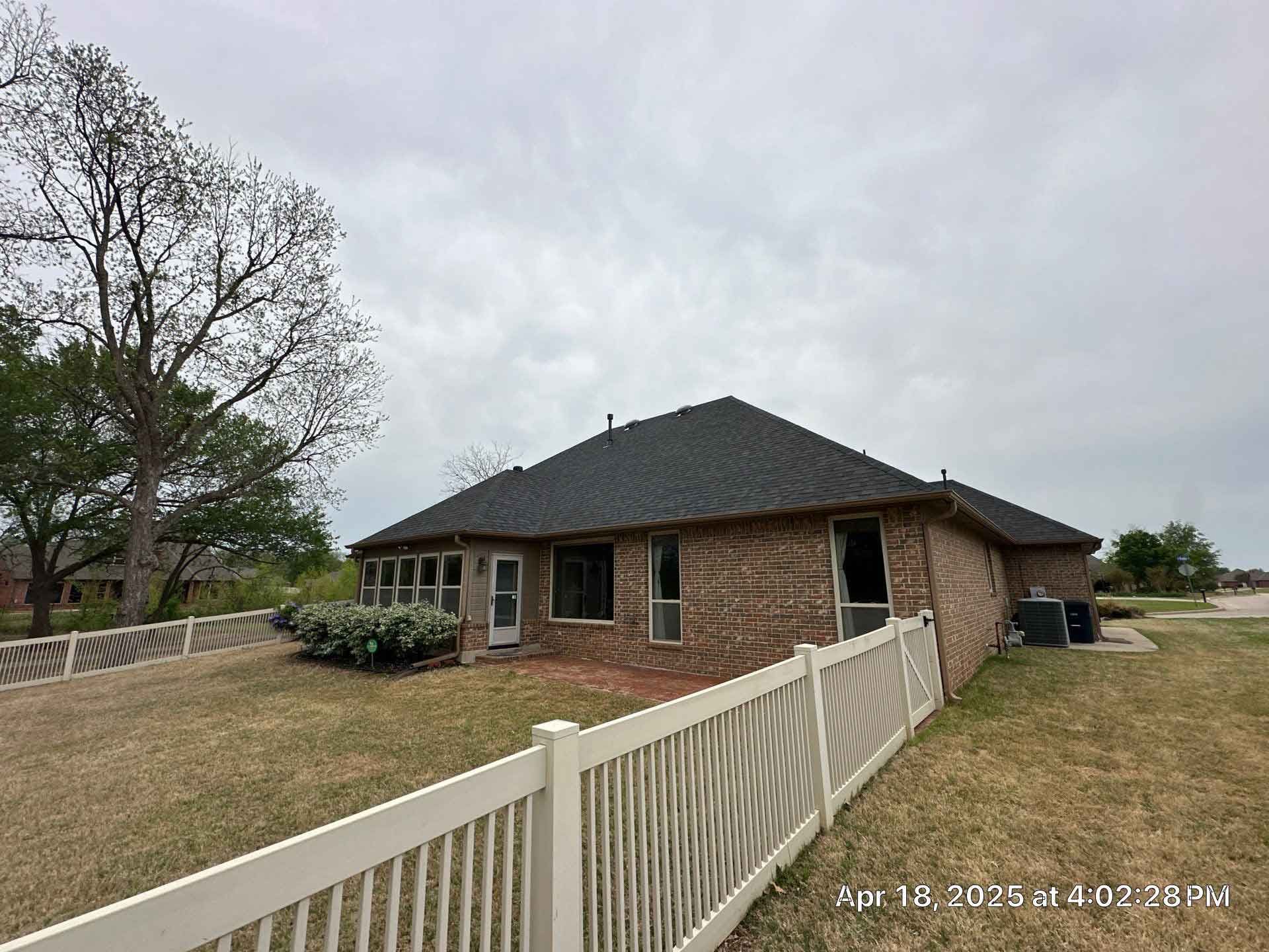 A brick house with a white fence in front of it.