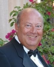 Smiling man in a tuxedo with pink flowers in the background