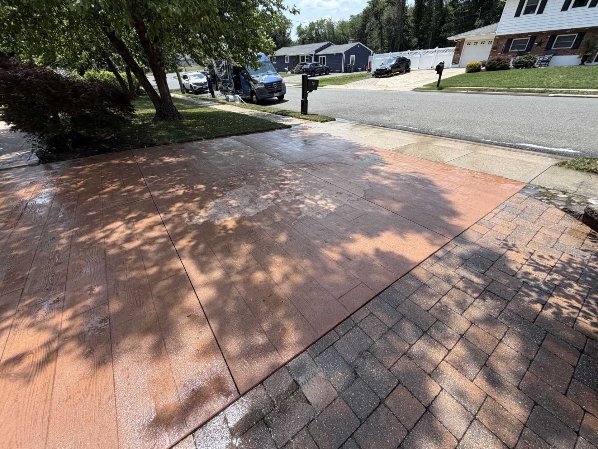 Large modern suburban house with a two-car garage, stone entry, and wide driveway under clear daylight