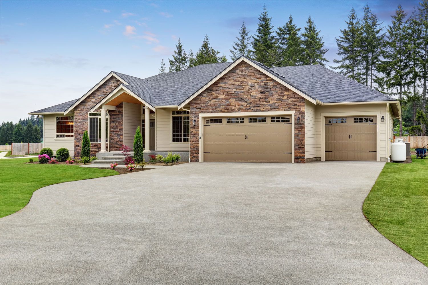 Single-story brick house with a large driveway, three-car garage, and manicured lawn.