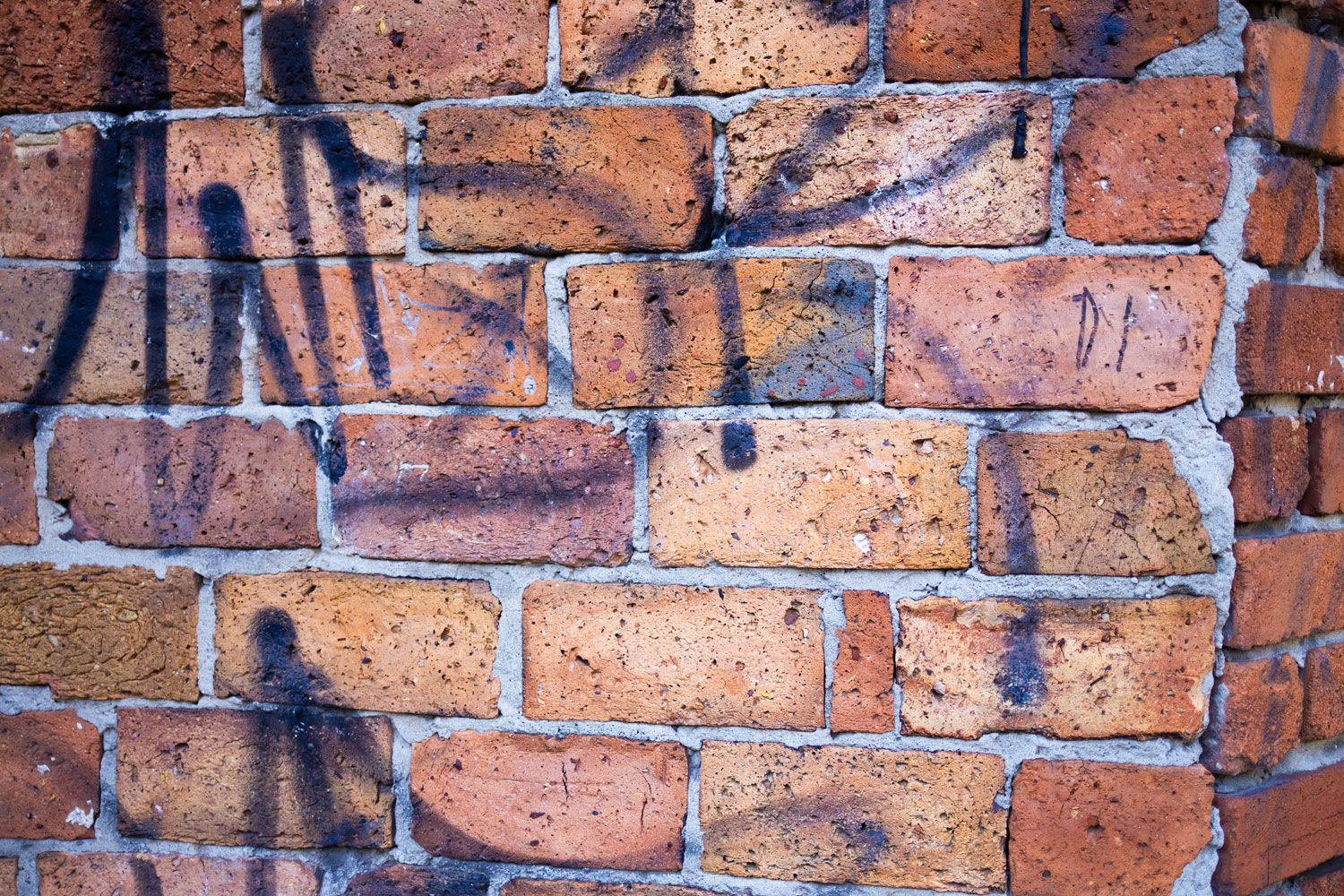 Graffiti on a weathered brick wall with dark blue and black spray paint markings