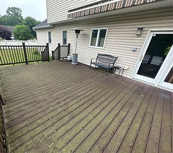 Wooden backyard deck beside a house with a bench, door, and fence, viewed from an angle