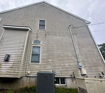 Side view of a beige vinyl-sided house with windows, utility meters, and an outdoor AC unit.