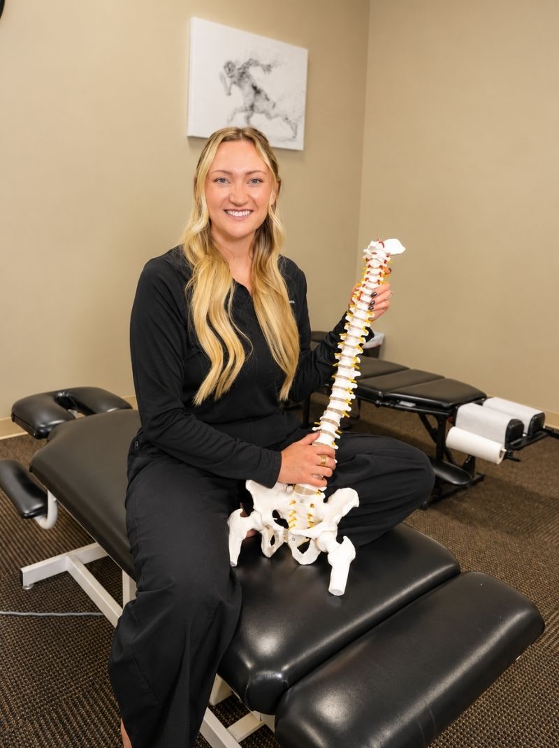 Chiropractor holding a spine model to explain herniated and bulging discs at Raise Chiropractic in Littleton, Colorado