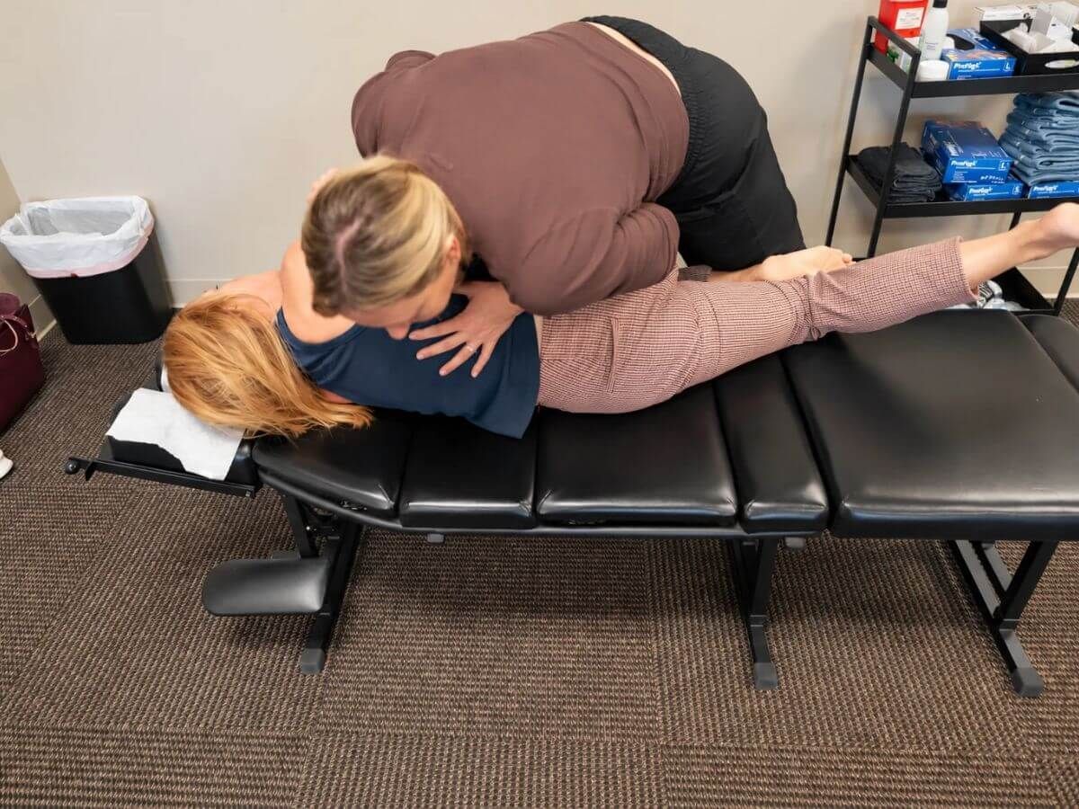 Chiropractor performing a side-lying hip adjustment on a female patient at Raise Chiropractic in Littleton, Colorado