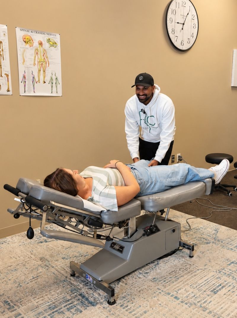 Dr. Neal examining a female patient's knee while she lies on a chiropractic table at Raise Chiropractic in Littleton, Colorado