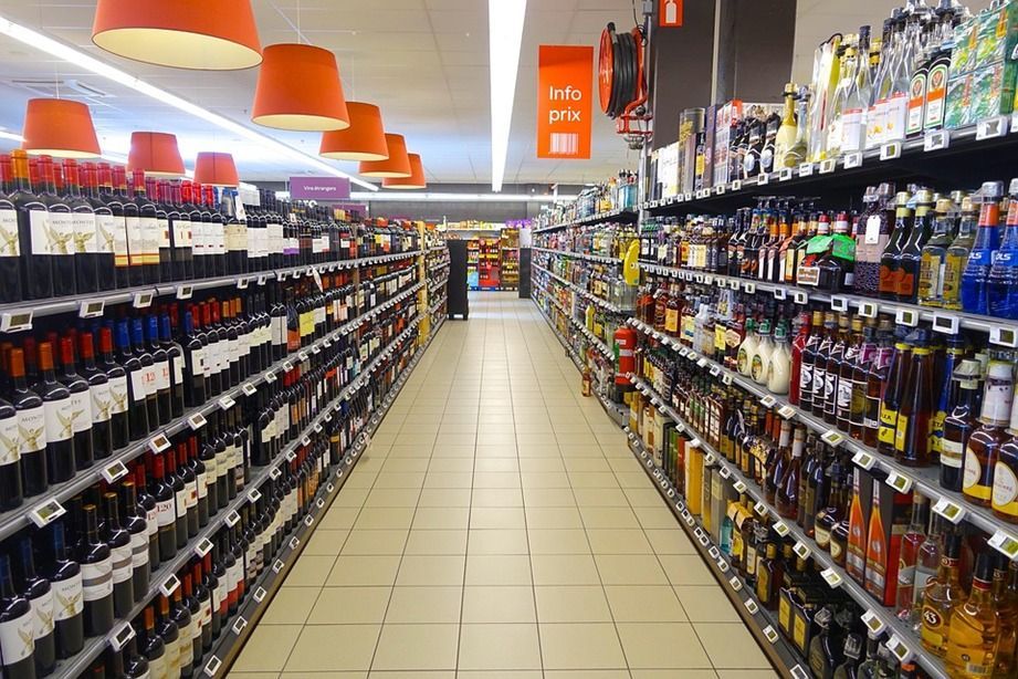 Estantes de vino y licor en un pasillo bien iluminado de una tienda de comestibles con RFID protegiendo inventarios