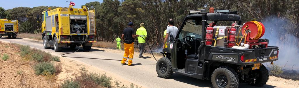 A group of fire trucks are driving down a dirt road.