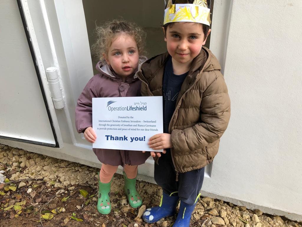 A boy and a girl are standing next to each other holding a thank you sign.
