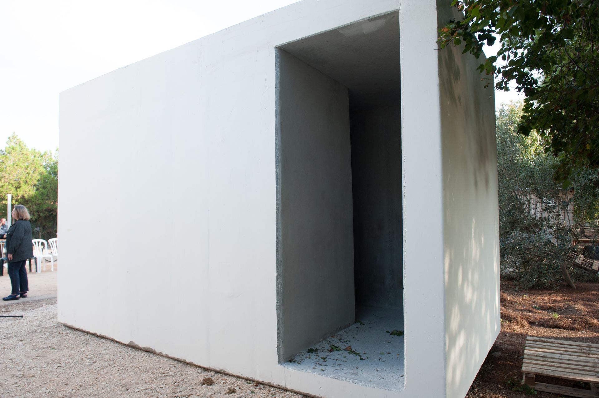 White rectangular outdoor structure with a large open doorway in a park setting