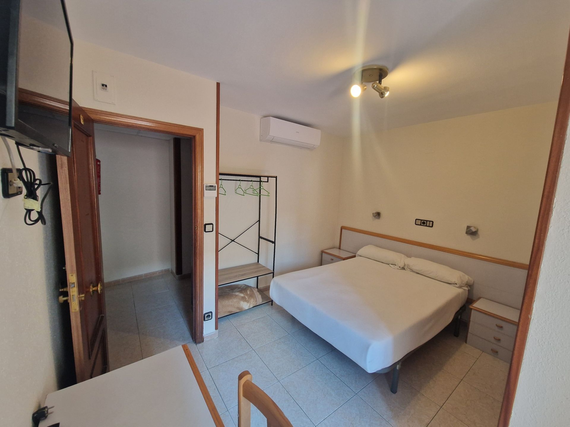 Un dormitorio con una cama, dos mesas de noche y una ventana.