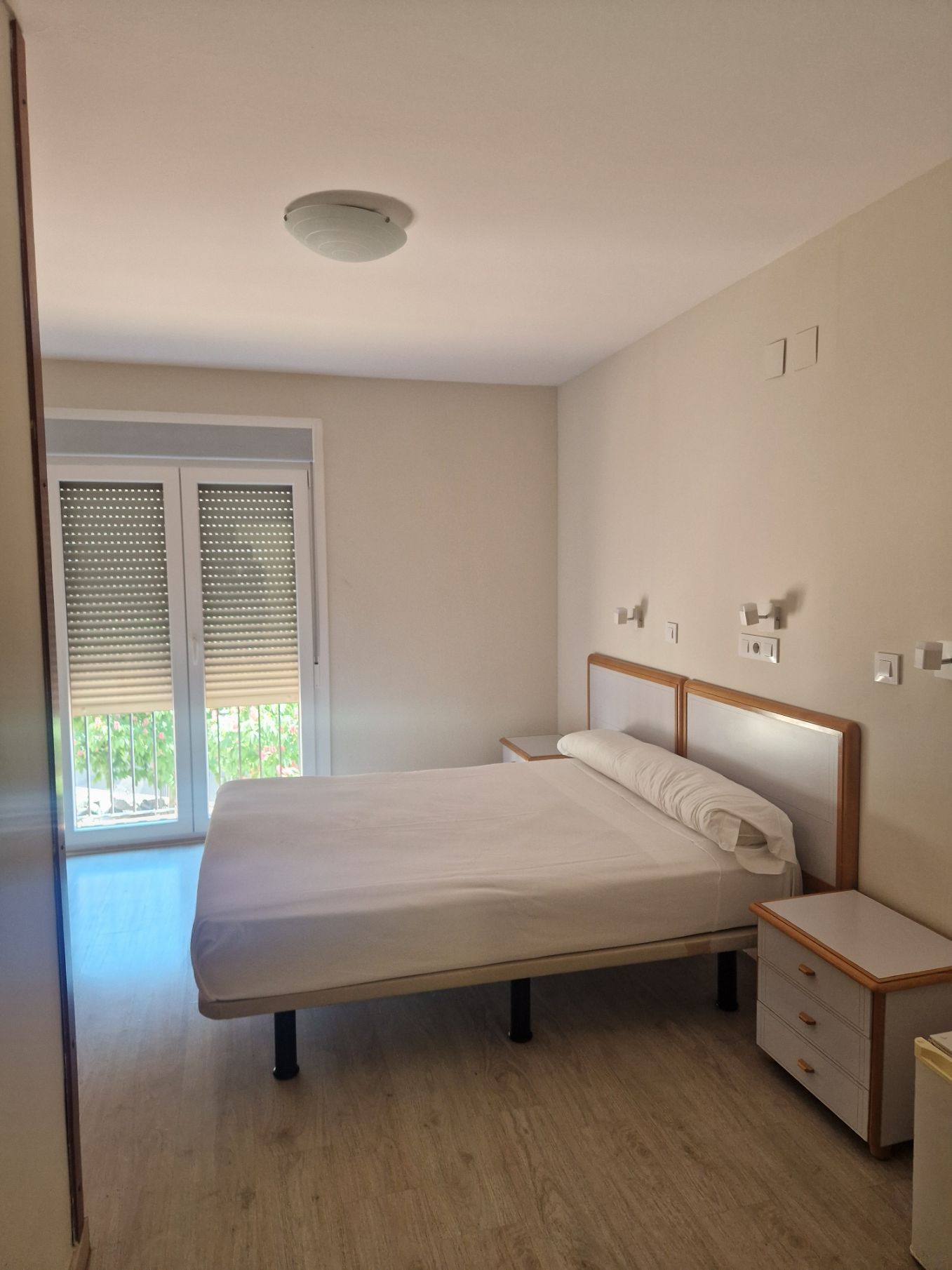 Una cama con sábanas blancas y almohadas marrones en una habitación de hotel.