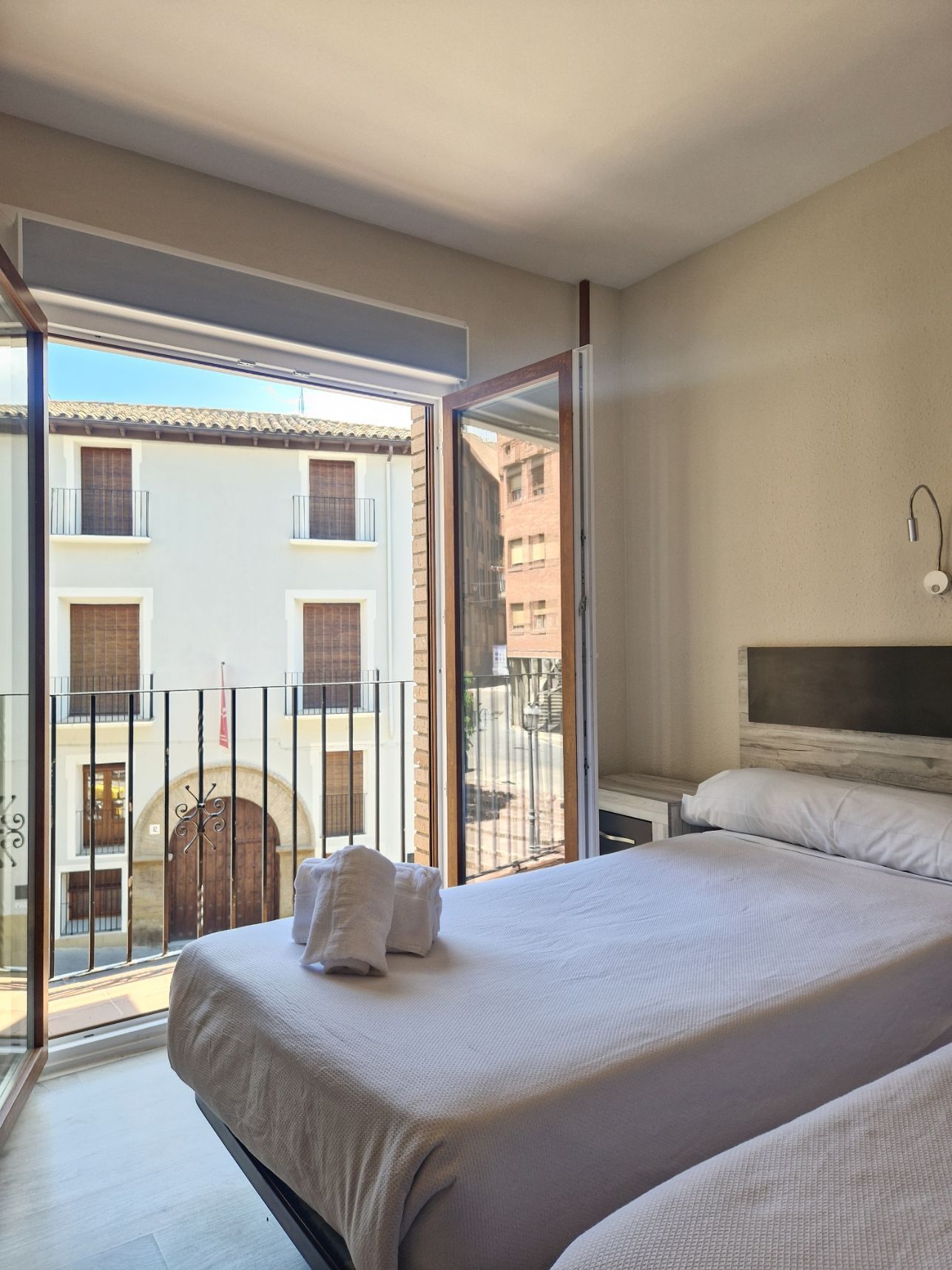Habitación luminosa con puerta de balcón abierta y vistas a los edificios vecinos.