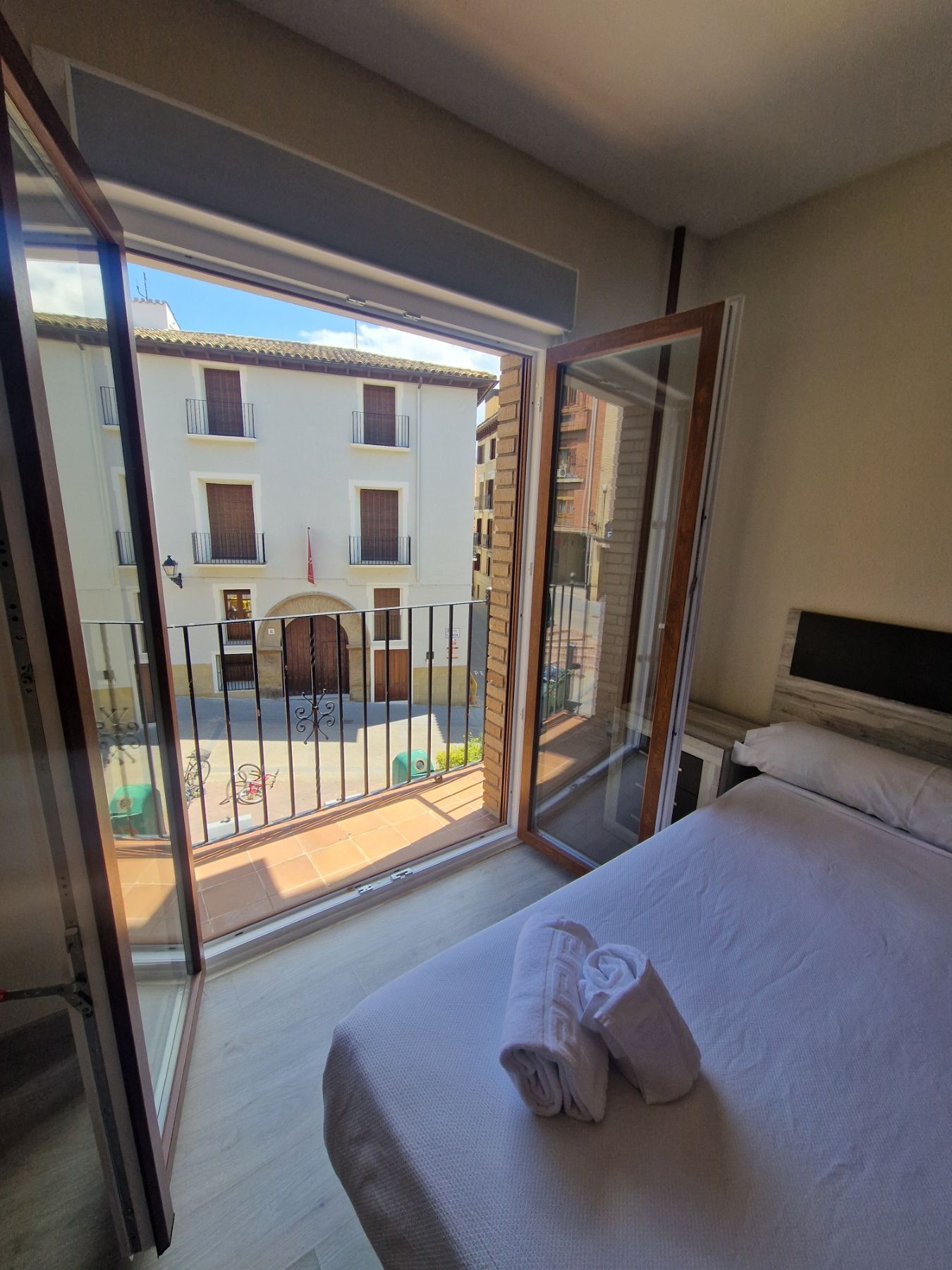Habitación con puertas que dan a un patio y una cama con toallas blancas dobladas.