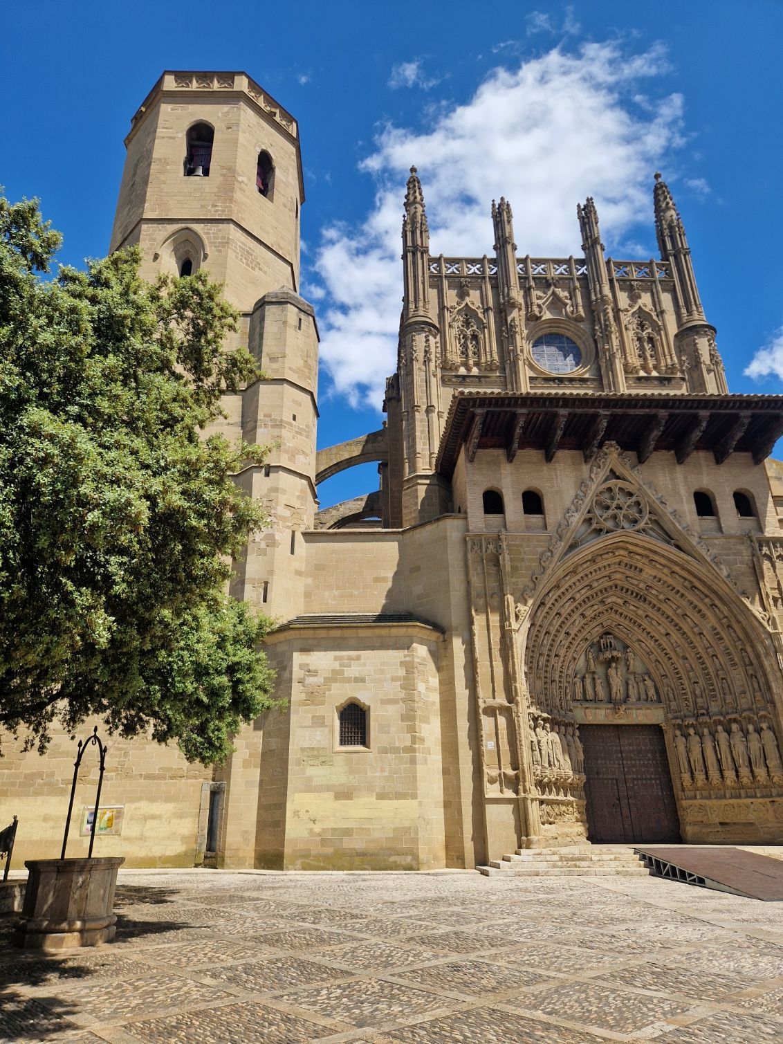 Catedral histórica de piedra con campanario y fachada gótica ornamentada bajo un cielo azul.