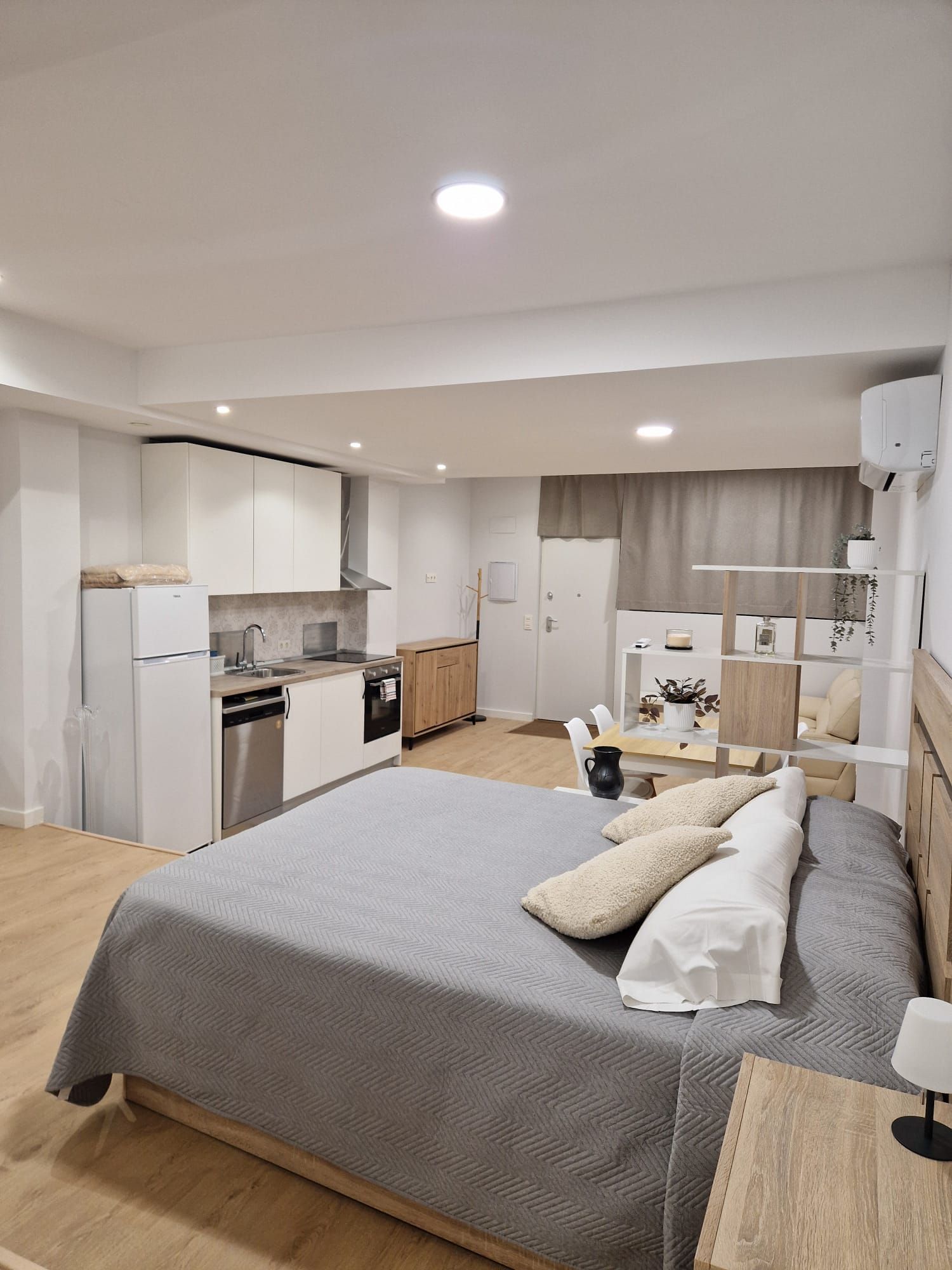 Apartamento tipo estudio moderno con cama, cocina pequeña, escritorio